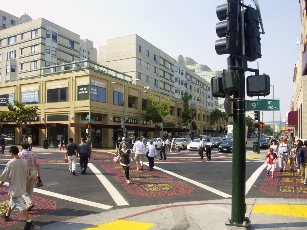 a wide photo of an intersection in chinatown with a decorative artistic crosswalk spanning the entire distance