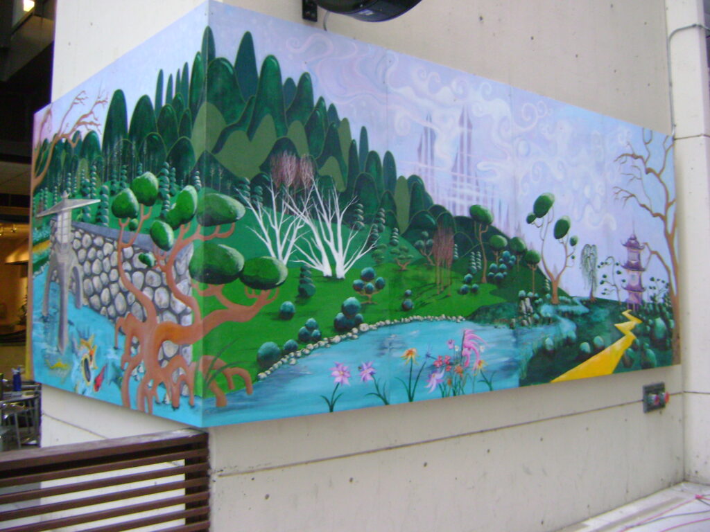 Image of mural on the corner of a building. The mural features a nature scene including a creek and tree-filled hillside.