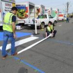Photo of temporary crosswalk installation by two people in bright vests