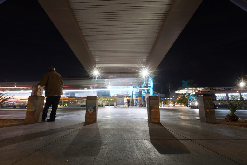 Image of Bonneville Transit Center at nightime. Vertical columns display messaging telling people to stay two arms apart.