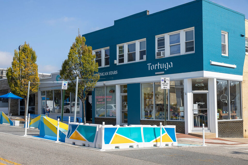 artistic barriers in front of a blue commercial building creating new sidewalk space