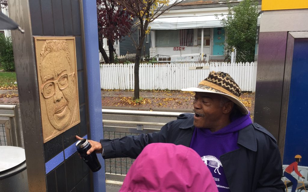 Image of artist and activist Melvin Giles discussing an art piece located on the Green Line in Saint Paul, MN.