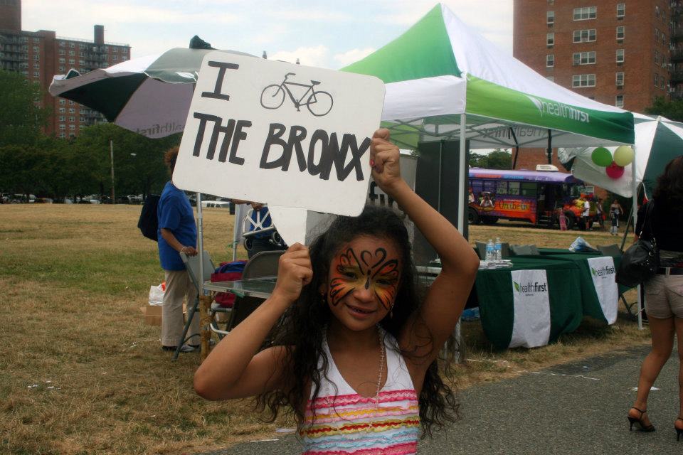 a young girl with a sign that says "I bike the bronx"