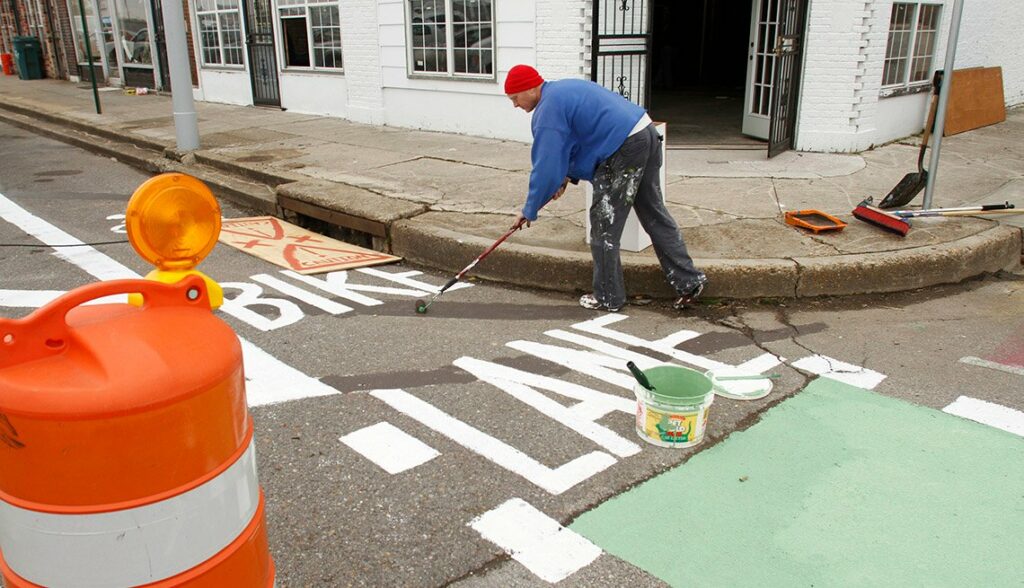 Image of person painting words onto a temporary bike lane in Memphis, Tennessee